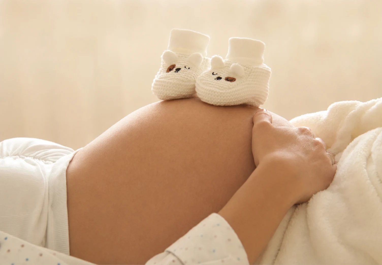 Baby booties resting on an expectant parent's belly